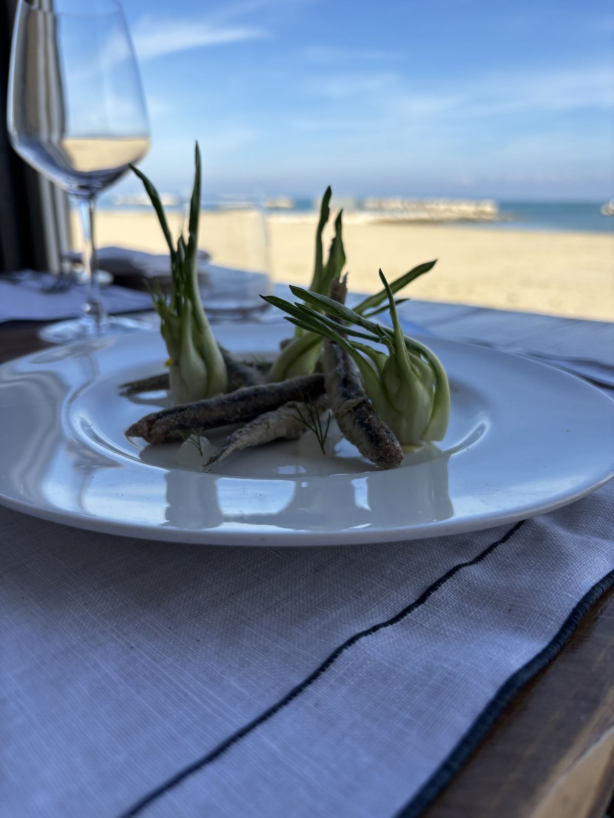 Alici fritte e puntarelle servite in veranda, con la spiaggia e il mare sullo sfondo