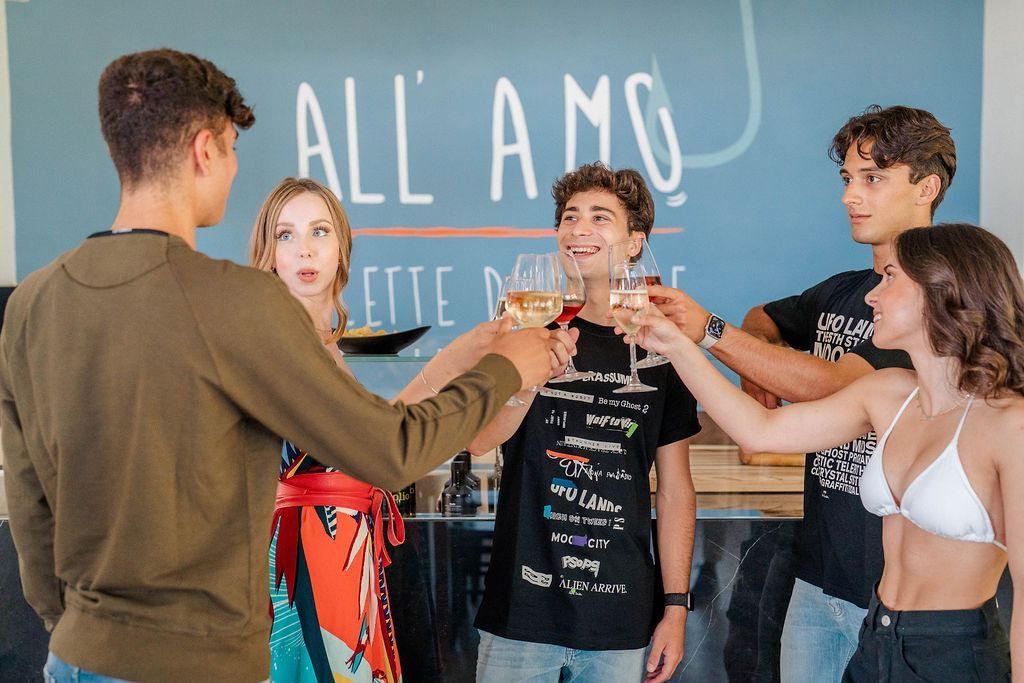 Un gruppo di amici brinda nella sala di All'Amo, davanti all'insegna del ristorante