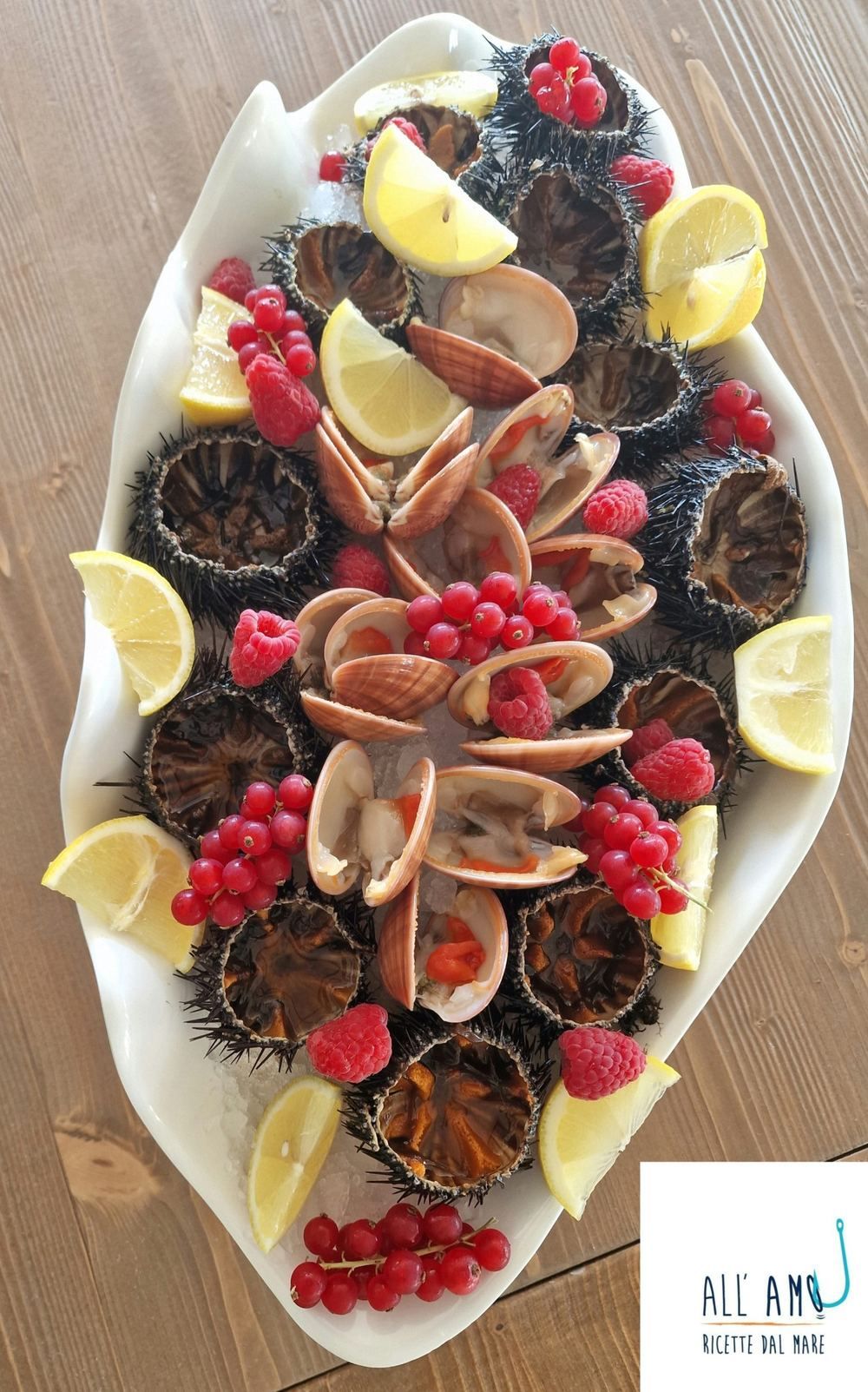 Frutti di mare crudi: ricci, vongole, lamponi e spicchi di limone