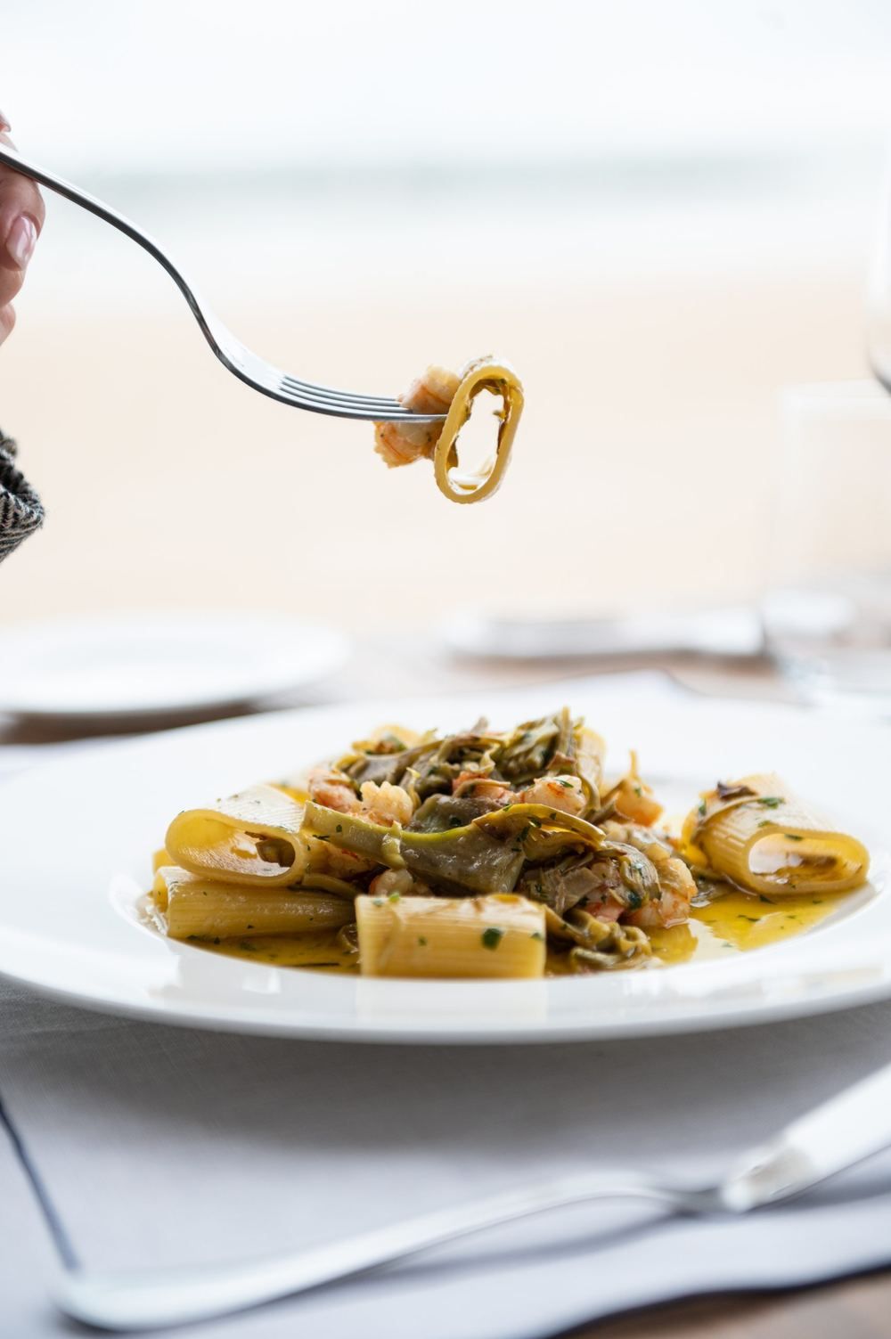 Piatto di pasta ai frutti di mare servito in veranda, con il mare sullo sfondo